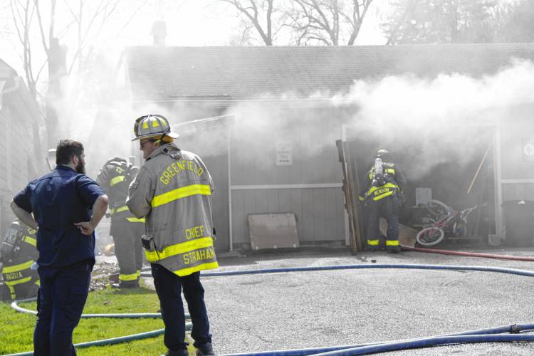 Homeowner Jeff Andrews and Greenfield Fire Chief Robert Strahan stand next to each other as firefighters extinguish a fire at Andrews’ garage on Homestead Avenue on Wednesday afternoon.