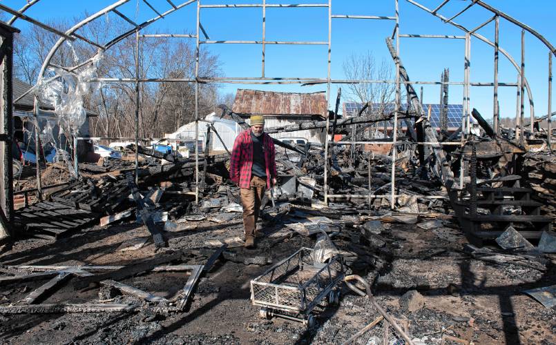 Ryan Voiland, a co-owner of Red Fire Farm in Granby, walks through the burnt greenhouse on Feb. 20, and talks about the damage from a fire at the farm and what it will take to rebuild.