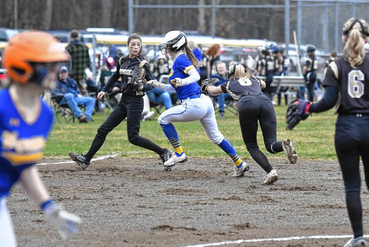 Mohawk Trail’s Rachel Pease avoids the tag taking third base between Pioneer’s Allison Clary and Kelly Baird, with ball, during the visiting Warriors’ 19-4 victory in Northfield on Thursday.