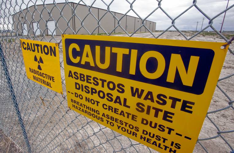 A caution sign hangs on a fence in front of a building that houses asbestos and depleted uranium in May 2015 at the EnergySolutions facility in Clive, Utah.