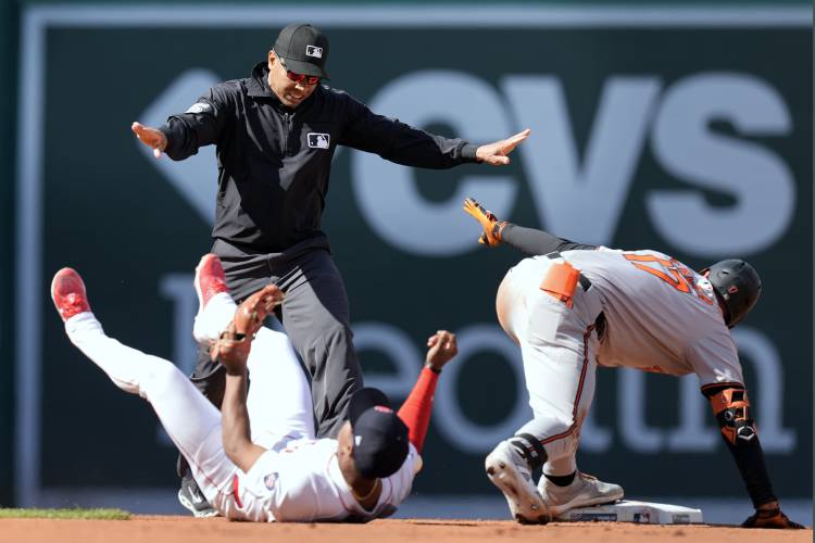 Boston Red Sox's Enmanuel Valdez lies on the field as Baltimore Orioles' Colton Cowser (17) is called safe with a two-run double during the fourth inning of an opening day baseball game at Fenway Park, Tuesday, April 9, 2024, in Boston. (AP Photo/Michael Dwyer)