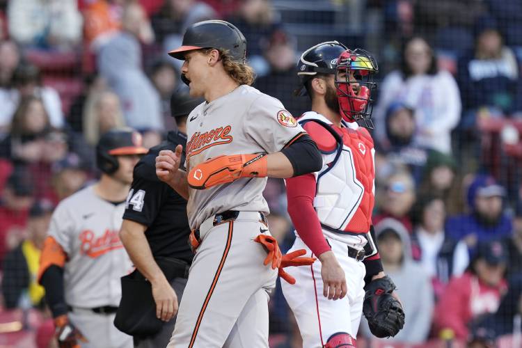 Baltimore Orioles' Gunnar Henderson scores in front of Boston Red Sox's Reese McGuire ion a single by Anthony Santander during the ninth inning of an opening-day baseball game at Fenway Park, Tuesday, April 9, 2024, in Boston. (AP Photo/Michael Dwyer)