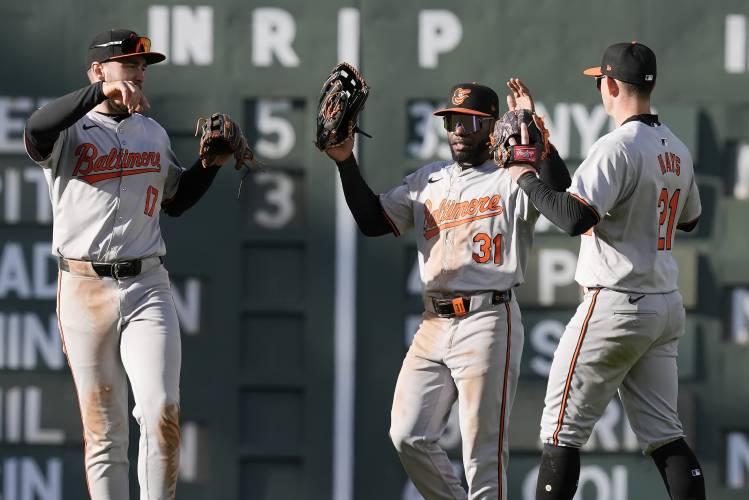Baltimore Orioles' Colton Cowser (17), Cedric Mullins (31) and Austin Hays (21) celebrate after defeating the Boston Red Sox during an opening-day baseball game at Fenway Park, Tuesday, April 9, 2024, in Boston. (AP Photo/Michael Dwyer)