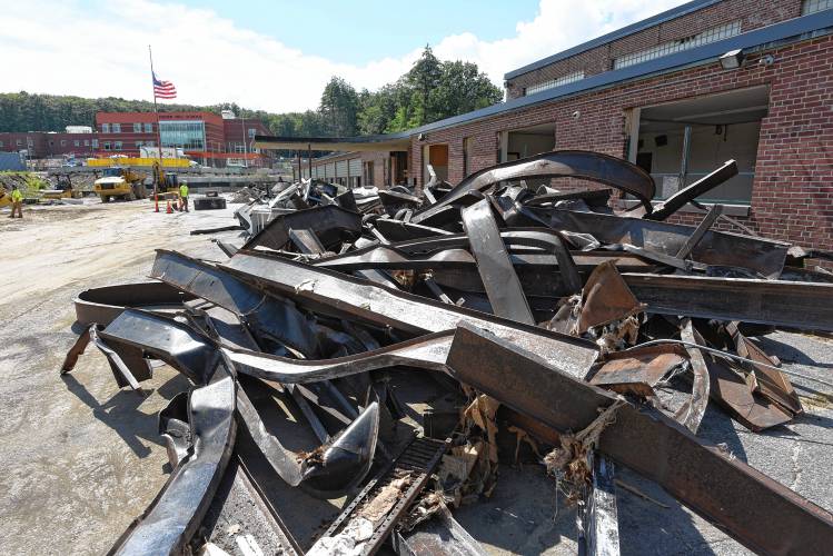 A pile of steel from Dexter Park Innovation School in Orange, which is being demolished following the renovation and expansion of Fisher Hill Elementary School, pictured in the background.  