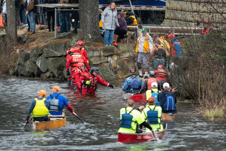Firefighters and dive team members help canoeists get out of the water after crossing the finish line in the 59th running of the River Rat Race on Saturday.