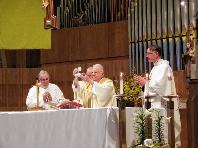 The Rev. Timothy Campoli elevates the sacred host during the Eucharist at a Mass celebrated at Blessed Sacrament Church in Greenfield on April 6, the 50th anniversary of his ordination as a Catholic priest.
