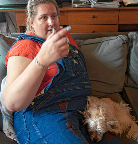 Rose Lynch talks about her role in the Western Mass Arm Wrestling League on her couch with her dog Ripley. Lynch is organizing an event called the Pulaski Pull Down on Jan. 27. She is wearing the overalls she wears as part of her character when she takes part in the arm wrestling competitions. Her character is called Virginia from West Virginia, inspired by her grandmother who Lynch describes as reminding her of Rosie the Riveter. “She was a housewife her whole life but she was bad ass,” said Lynch about her grandmother.