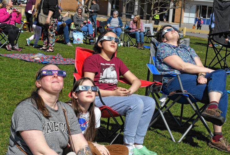Magen MacDougall, her daughter Emma Goulding, Hazel Singh and her mother Joanna Singh, all of Northfield, gaze at the solar eclipse at a viewing event held at Pioneer Valley Regional School on Monday.