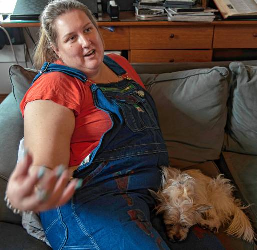 Rose Lynch talks about her role in the Western Mass Arm Wrestling League on her couch with her dog Ripley. Lynch is organizing an event called the Pulaski Pull Down on Jan. 27. She is wearing the overalls she wears as part of her character when she takes part in the arm wrestling competitions. Her character is called Virginia from West Virginia, inspired by her grandmother who Lynch describes as reminding her of Rosie the Riveter. “She was a housewife her whole life but she was bad ass,” said Lynch about her grandmother.