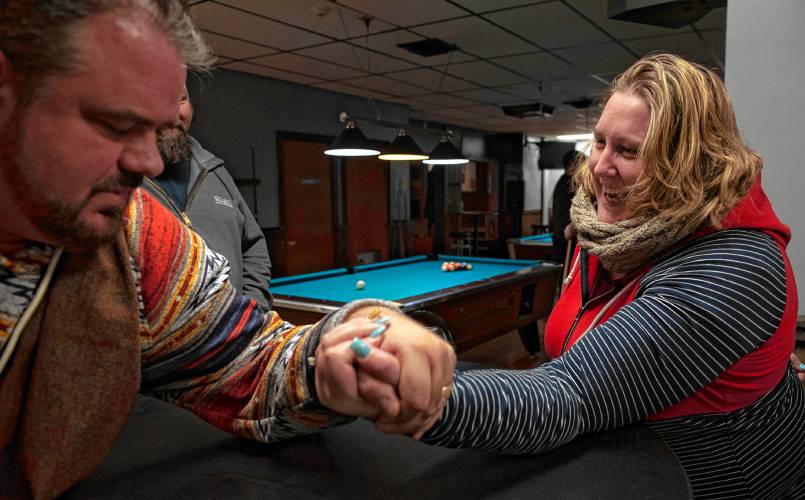 Rose Lynch laughs as Donald Carberry, a co-sponsor for the arm wrestling event The Pulaski Pull Down, beats her while arm wrestling at the Se7ens Sports Bar and Grill in Easthampton Thursday evening, Dec. 6, 2023.