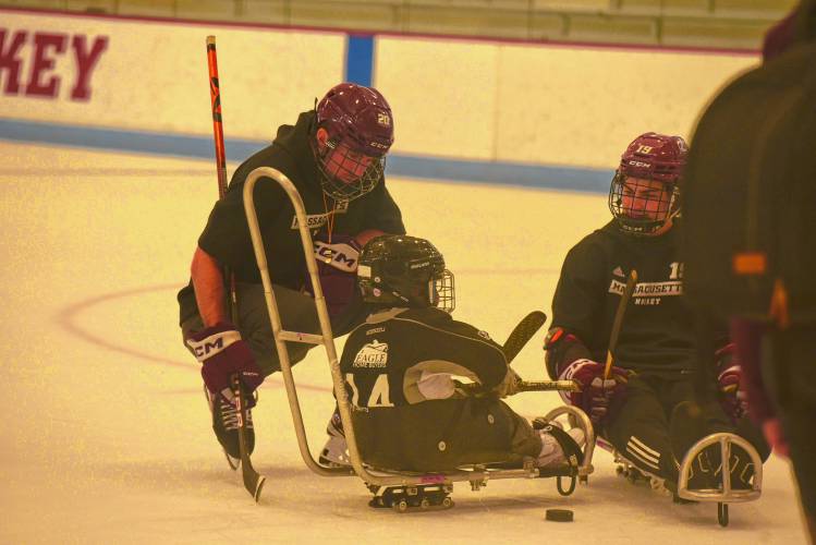 UMass hockey's Liam Gorman, left, gives guidance to youth sled hockey player during CHD's All In Sled Hockey Open Skate on Monday at the Mullins Center practice rink in Amherst.