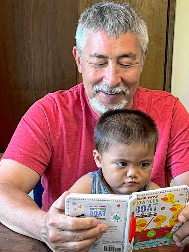 The Rev. James Koyama, pictured here reading a book to his grandson, is the pastor at the First Congregational Church of Montague.