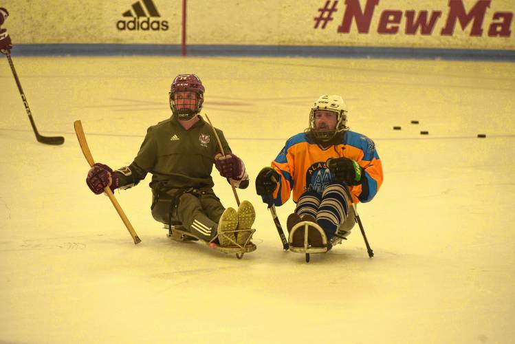 Ryan Lautenbach of UMass hockey team, left, works with sled hockey players during CHD's All In Sled Hockey Open Skate on Monday at the Mullins Center practice rink in Amherst.