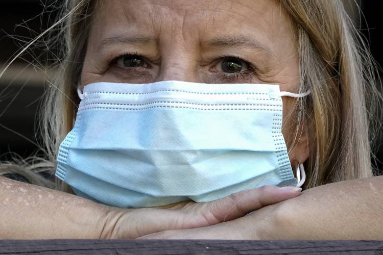 A woman wears a mask at her home after previously having COVID-19. The Centers for Disease Control and Prevention is considering loosening isolation rules for people who get the disease.