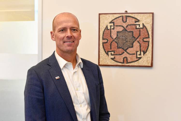 Dean of Spiritual and Ethical Life at Deerfield Academy, Jan Flaska, next to a Jordanian mosaic from Madaba that hangs in the school’s library.