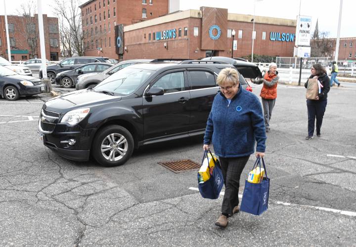 Volunteer Mary Rawls carries donations for the 20th annual Supper for Six food drive to the United Way of the Franklin & Hampshire Region’s Davis Street offices in Greenfield on Thursday.