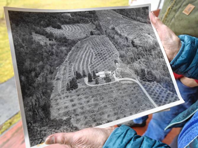 Susan Flaccus holds a circa 1970 aerial photo of her family’s home, Kenburn Orchards, in Shelburne.