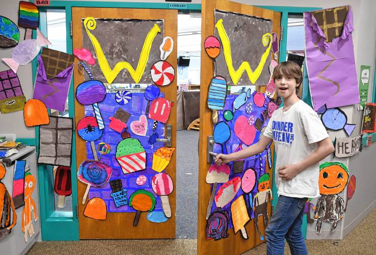 Sixth grade student Sam Giannelli opens the doors to the Willy Wonka workshop where children made candies out of art supplies for Conway Grammar School’s celebration of Read Across America Day.