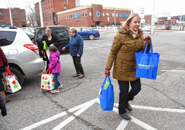 Volunteer Denise Mason carries donations for the 20th annual Supper for Six food drive to the United Way of the Franklin & Hampshire Region’s Davis Street offices in Greenfield on Thursday.