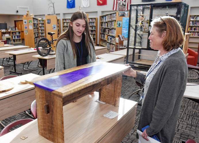 Ralph C. Mahar Regional School student Madilyn Moore shows the epoxy resin table she made out of walnut to educator Maureen Donovan at the Mahar Makers’ Makerfaire on Wednesday.