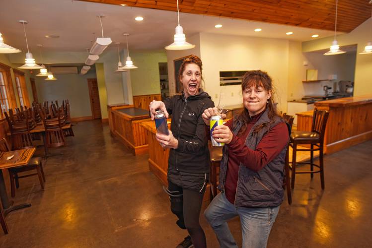 Anna Cronin, co-owner of Dirt Church Brewing Co. out of Vermont, and building co-owner Kristie Faufaw crack open a couple of Dirt Church beers in the former River Cafe space where Cronin plans to open a brew pub in Charlemont.