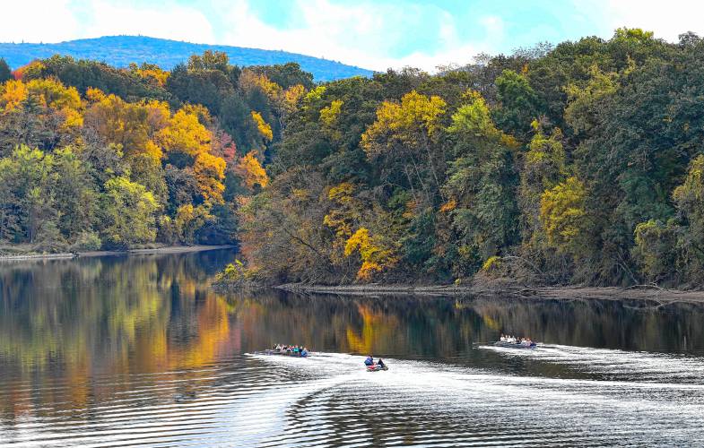 Two crew boats and a launch head down the Connecticut River in Northfield as the foliage approaches its peak.