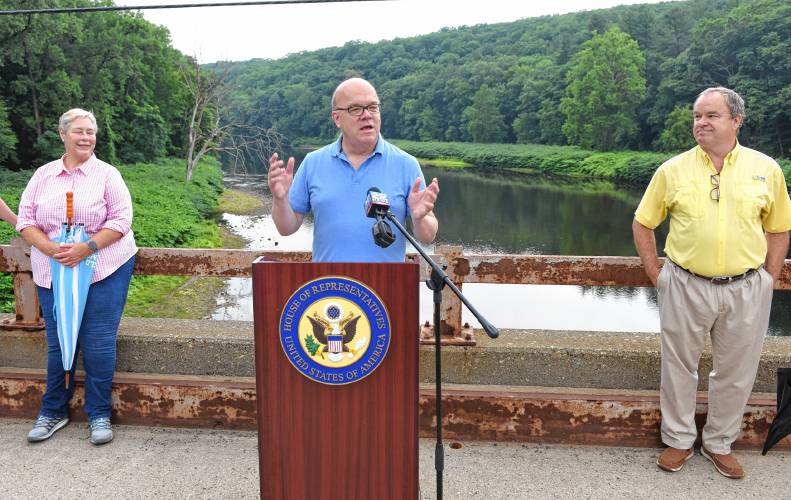 ABOVE: A fishing guide and fishermen on the Deerfield River are framed by one of the arches of the Bridge of Flowers in Shelburne Falls.RIGHT: Congressman Jim McGovern is flanked by Deerfield Selectboard members Carolyn Shores Ness and Tim Hilchey on the Stillwater Bridge over the Deerfield River in Deerfield in July 2022 to announce legislation seeking to add the river to the National Wild and Scenic Rivers System.