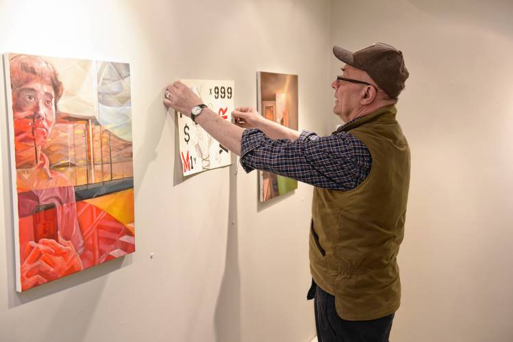 Artspace Community Arts Center Board President Stephen Hussey hangs artwork for the 50th annual Teen Art Show at the Mill Street gallery in Greenfield.