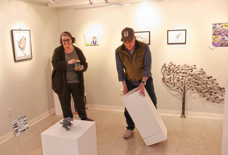 Office Manager Jillian Henry and Board President Stephen Hussey arrange artwork for the 50th annual Teen Art Show at Artspace Community Arts Center in Greenfield.