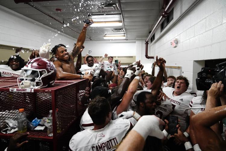 UMass football players celebrate in the locker room after defeating New Mexico State, 41-30, on Saturday in Las Cruces, N.M.