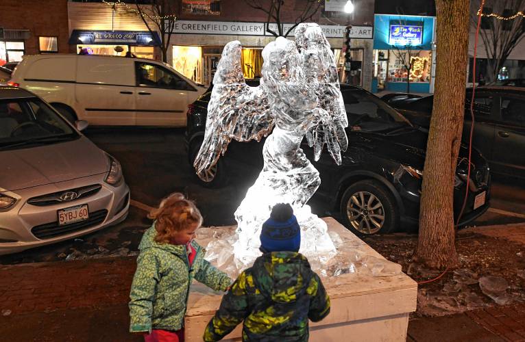 People check out an ice sculpture of an angel crafted by Athol resident Mark Bosworth on Friday night during the 102nd annual Winter Carnival in Greenfield.