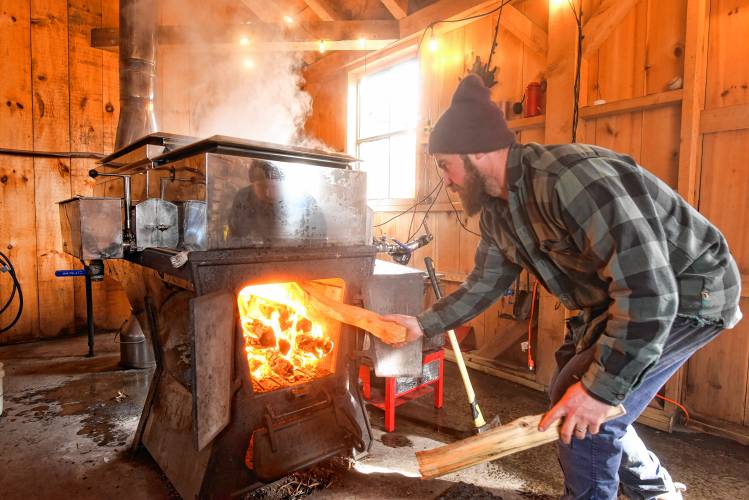 Rich Valcourt of Valcourt Sugar Shack in Petersham loads up the arch with wood as he boils down his recent haul of sap into maple syrup on Thursday. 