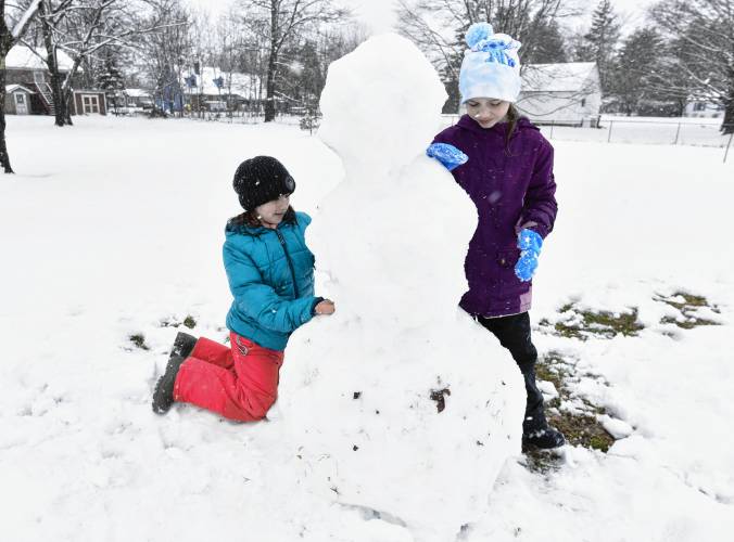 Self-proclaimed best friends Brooklyn Simon, 9, and Riya Clark, 9, build a snowman near their home in Turners Falls on Thursday afternoon.
