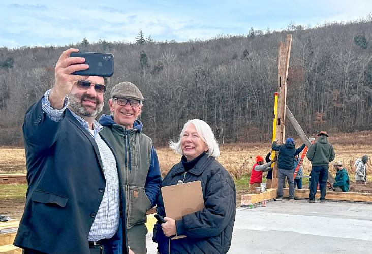 From left, state Sen. Paul Mark, Buckland Historical Society President Michael McCusker and Capital Campaign Chair Sue Samoriski take a selfie with the first beam of the restored Wilder Homestead barn on Tuesday.