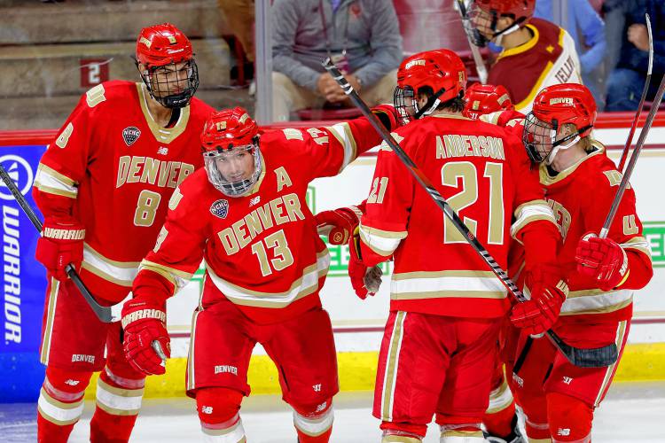 Denver forward Massimo Rizzo (13) is surrounded by defenseman Shai Buium (8), defenseman Kent Anderson (21) and forward Jack Devine (4) after a scoring a goal against Boston College earlier this season in Chestnut Hill.