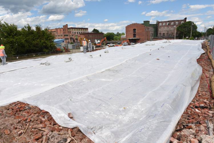 Workers cover the debris from the cereal factory fire in Orange in July 2022 with tarps.