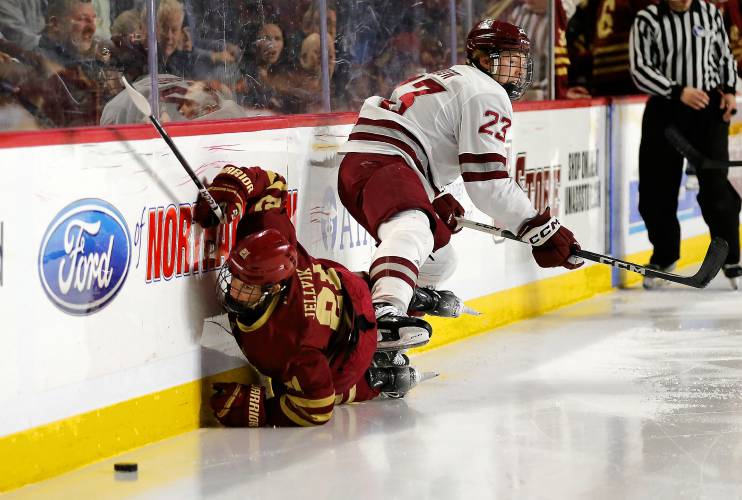 UMass defender Scott Morrow (23) knocks Boston College’s Oskar Jellvik (21) into the boards in the second period Friday night at the Mullins Center.