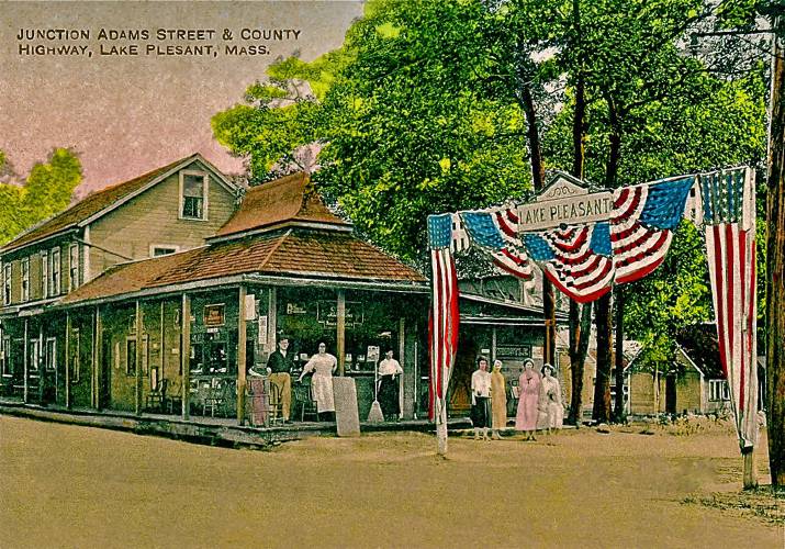 A postcard depicting the junction of Adams Street and the county highway in Lake Pleasant.