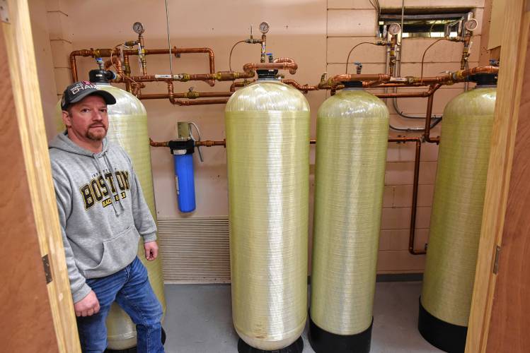 Eric Shufelt, maintenance director at Swift River School in New Salem, in the closet containing the four-tank filtration system for water at the school.