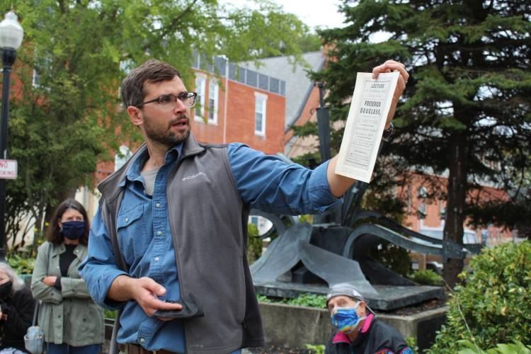 Greenfield High School history teacher Luke Martin, seen here at Veterans Mall in 2021 holding a newspaper advertisement for a Frederick Douglass lecture, led a walking tour around Greenfield highlighting local ties to the Underground Railroad and abolitionist movement.
