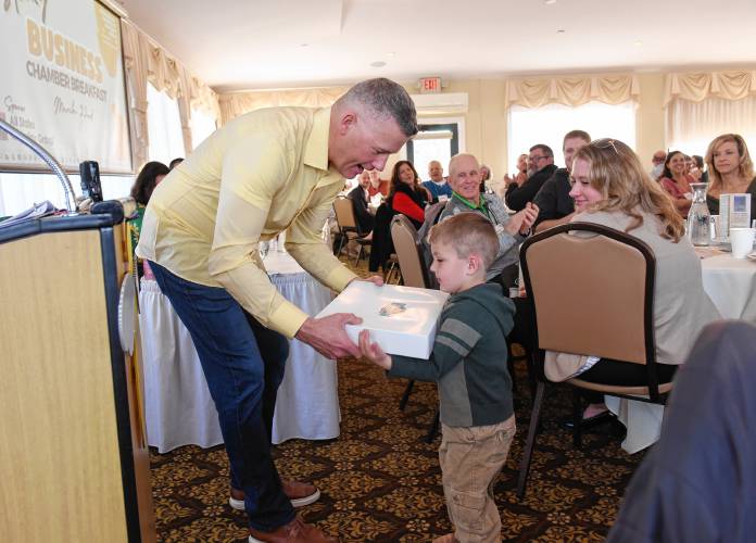 Wade Bassett, chair of the Franklin County Chamber of Commerce board of directors, gives a box of doughnuts from Adams Donuts to happy raffle winner Dylan Nelson, 3, of Greenfield, who was in attendance at the March chamber breakfast with his father, Michael Nelson.