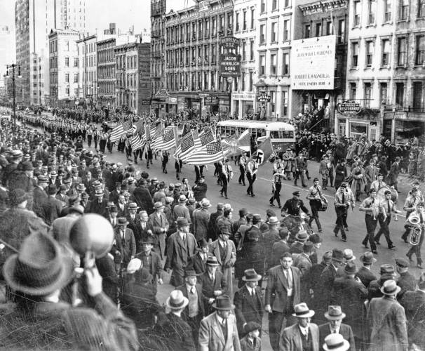 Members of the German American Bund, waving Nazi and American flags side by side, march in New York City in October 1937.