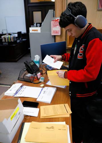Temporary worker Jimmy Serrano sends out mail-in ballots Friday afternoon at the Holyoke City Clerk’s Office.