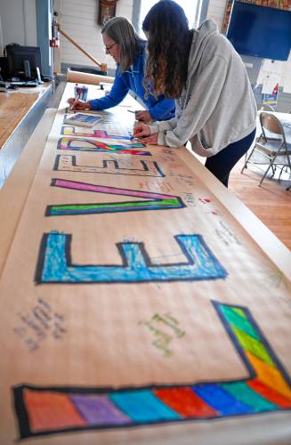 Kathleen Lafferty and Julianne Carolla, 12, work on the 250-foot story scroll at Leverett Town Hall during the town’s 250th anniversary celebrations on Saturday.