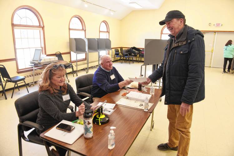 Susan Tandy Songer and Jeff Cole check Orange resident Larry Fisher in to vote in the Orange town election on Monday.