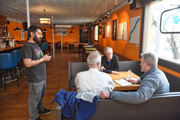 Bartender and server Joe Farina, left, takes a table’s food order at The Rendezvous in Turners Falls on Wednesday. A proposed ballot question would increase service wages for tipped workers and allow businesses to create a tip pool for all employees.