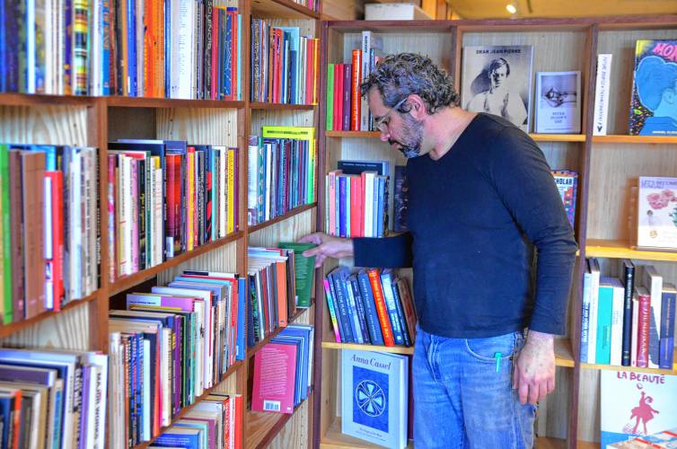 Co-owner Adam Tobin shelves books at Unnameable Books on Avenue A in Turners Falls.