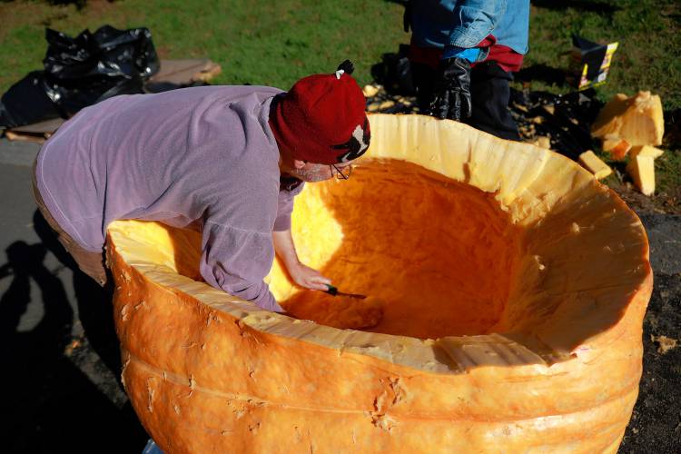 Florence resident Dave Rothstein hollows out a giant pumpkin at Adhesive Applications, where the pumpkin was weighed, Friday afternoon in Easthampton. Rothstein hopes to paddle the pumpkin down the Connecticut River in a  record attempt.