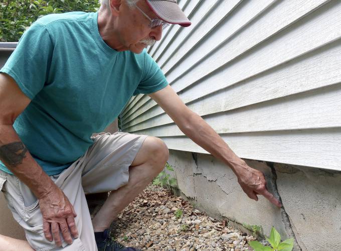 Ken Fisher points to one of the cracks in the foundation of his home in Vernon, Connecticut in July 2019.