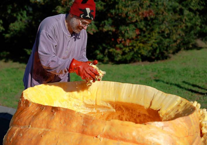 Florence resident Dave Rothstein hallows out a giant pumpkin at Adhesive Applications, where the pumpkin was weighed, Friday afternoon in Easthampton. Rothstein hopes to paddle the pumpkin down the Connecticut River in a world record attempt.